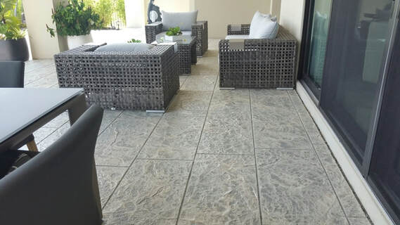 Picture showing modern sofas and patio table on concrete patio floor finished in a modern gray textured stamped concrete pattern.