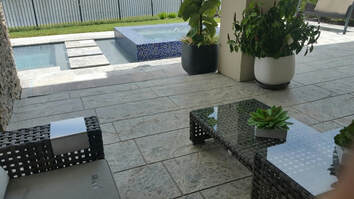 Picture of a patio overlooking swimming pool.  Deck is finished in a modern stamped concrete design.